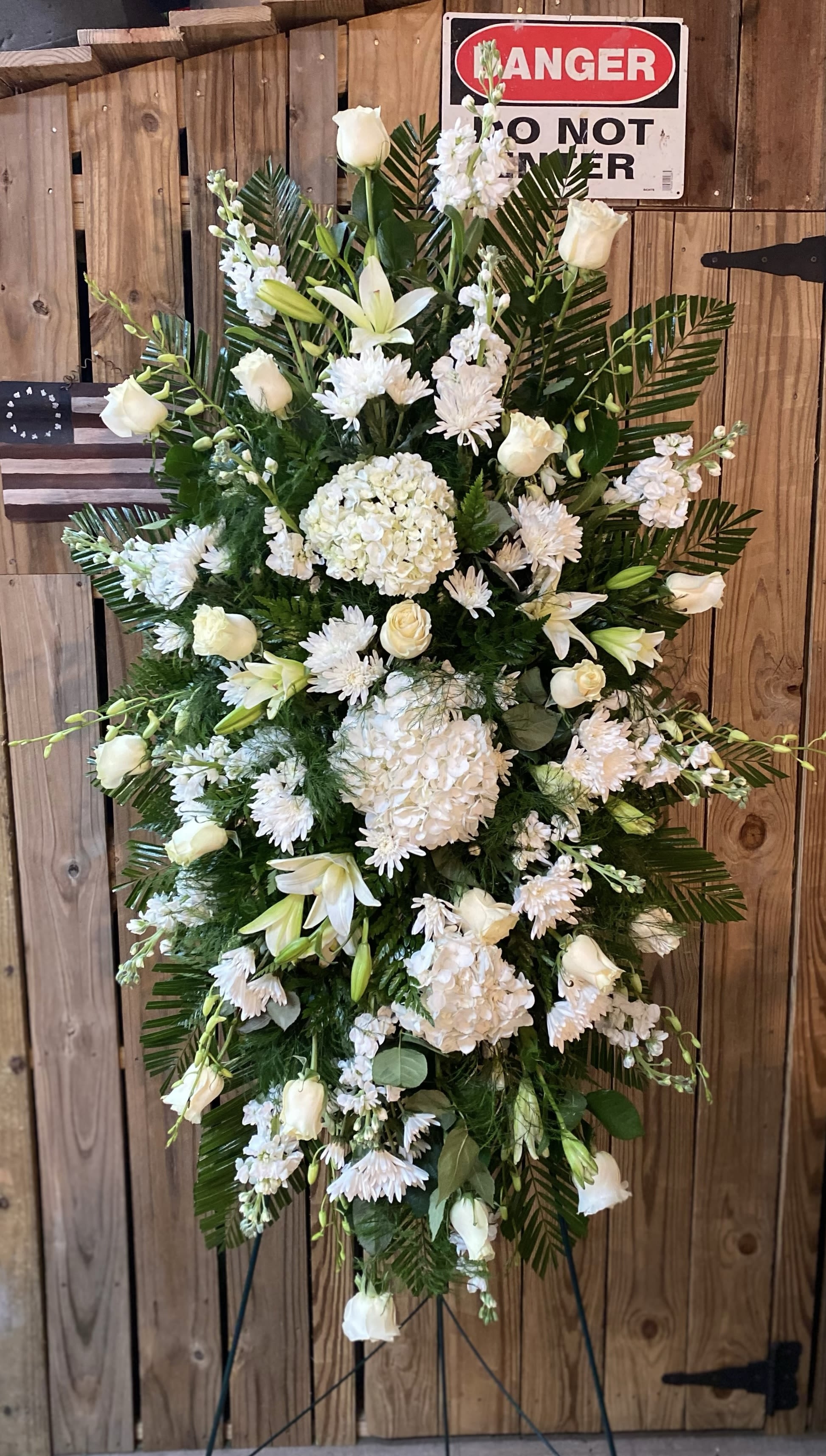 White funeral spray with roses, lilies, and hydrangeas on a stand
