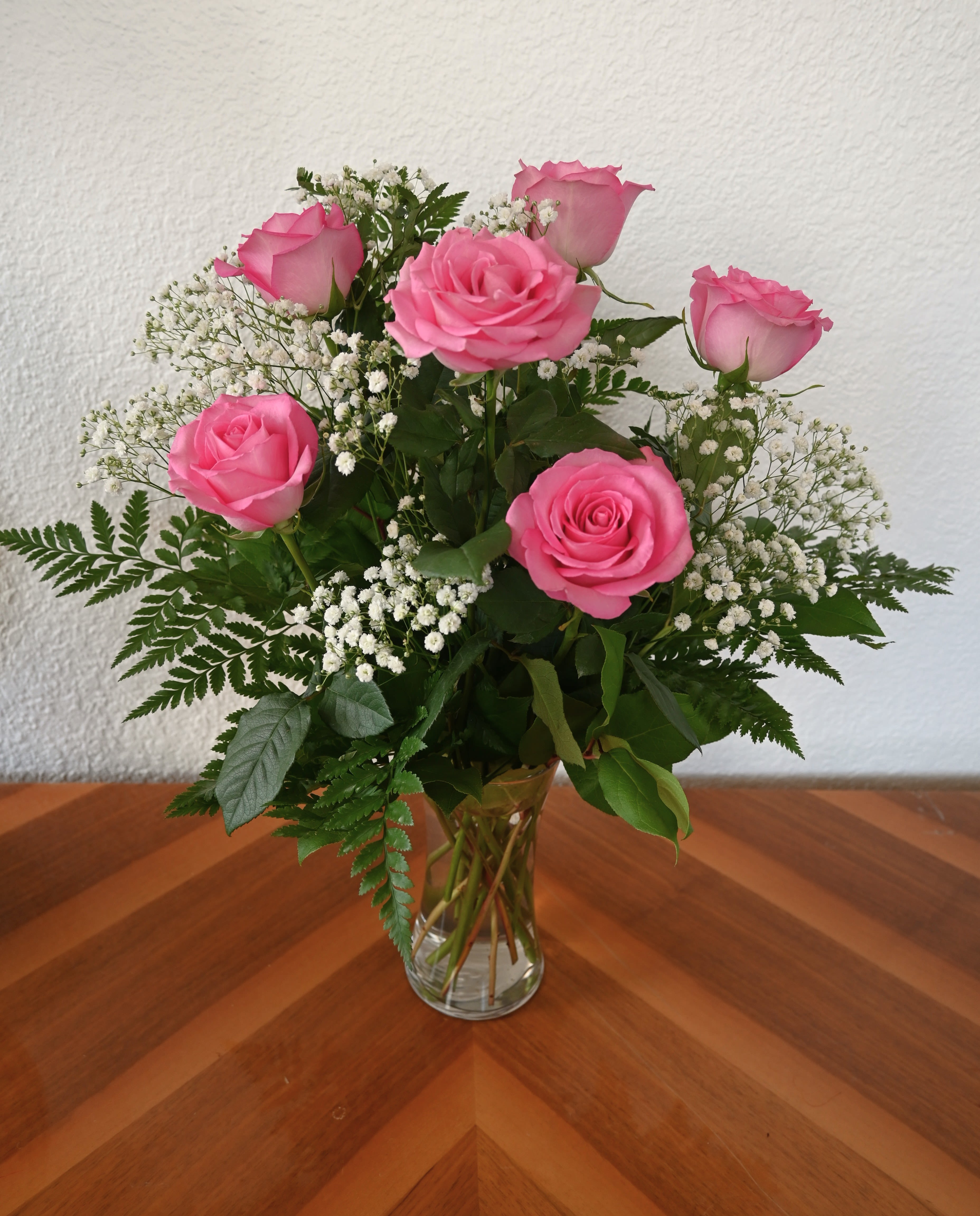 Pink roses arranged in a clear glass vase with white baby's breath