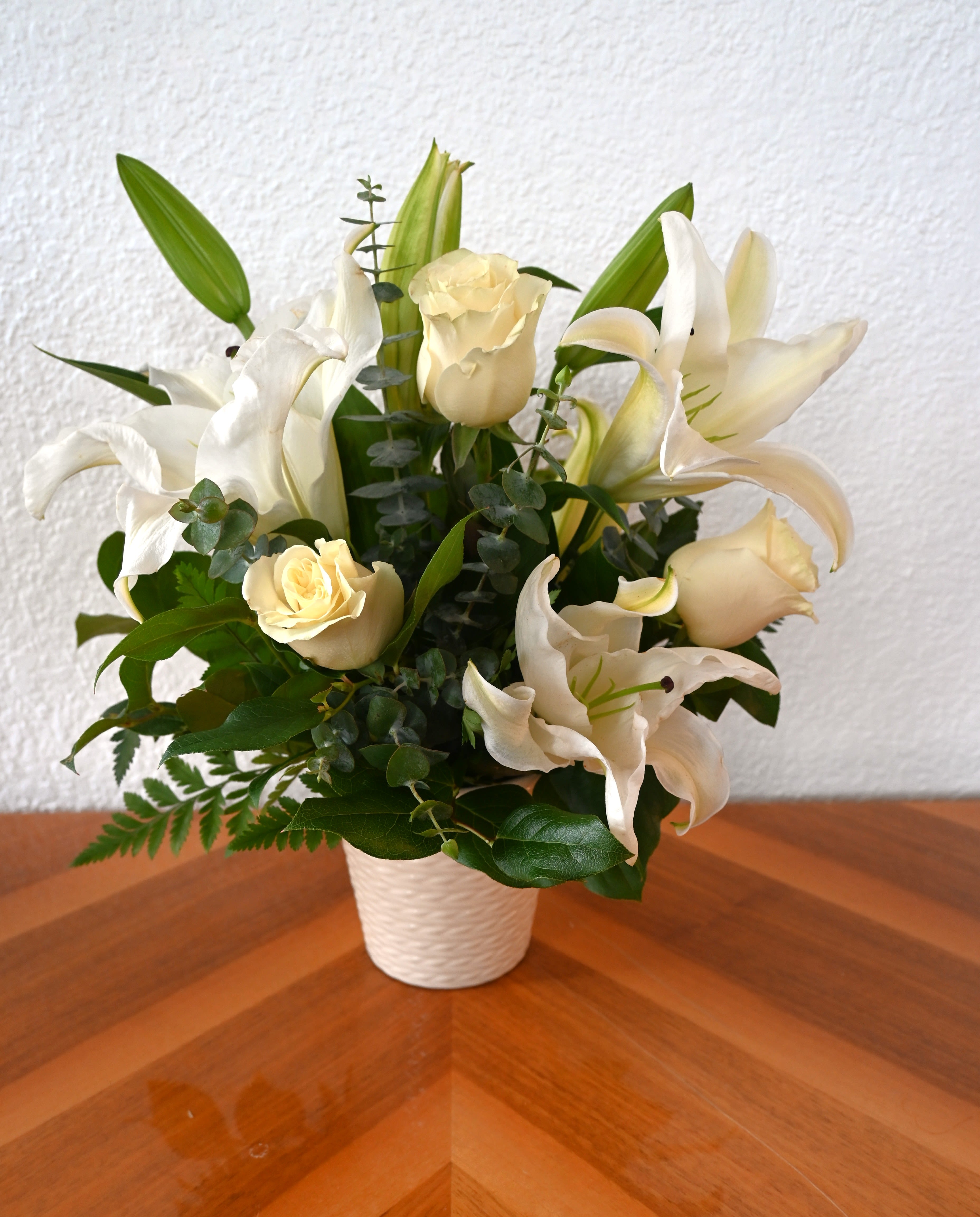 Elegant Embrace - Wrap them in comfort with our Elegant Embrace. With the timeless combination of white lilies and roses, it is sure to fill the space with comfort and peace.