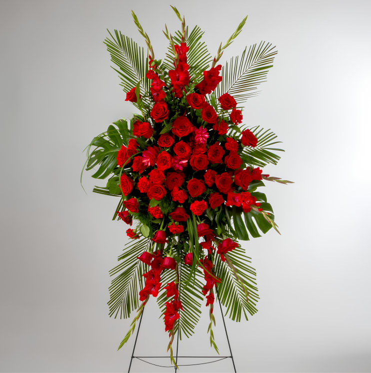 Forever Feelings by BloomNation™ - Red is the color of love and this standing spray displays it with luxurious style. Red roses and palms come together with other red and greenery to create a beautiful salute.