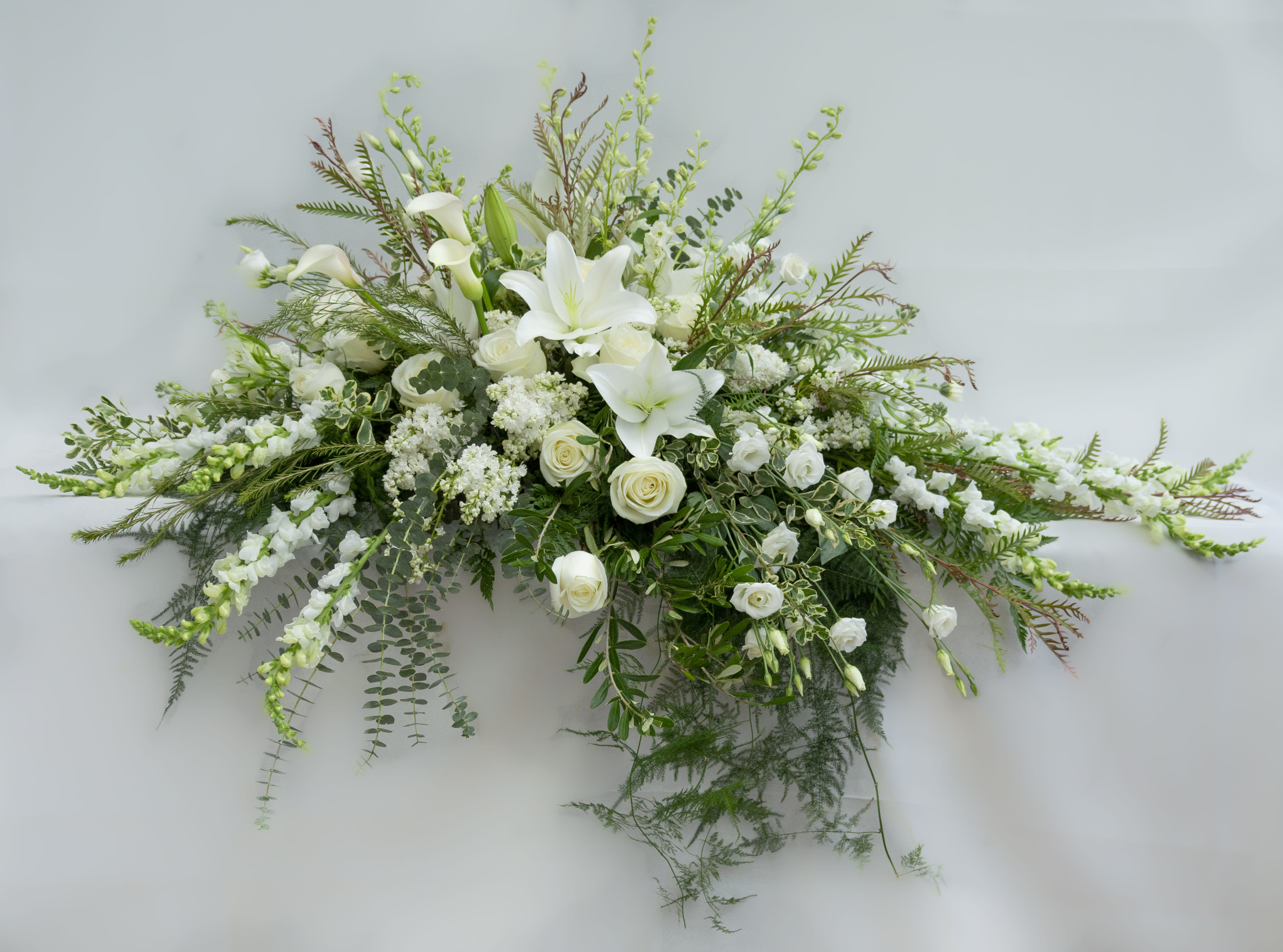White lilies and roses in a long floral spray with greenery