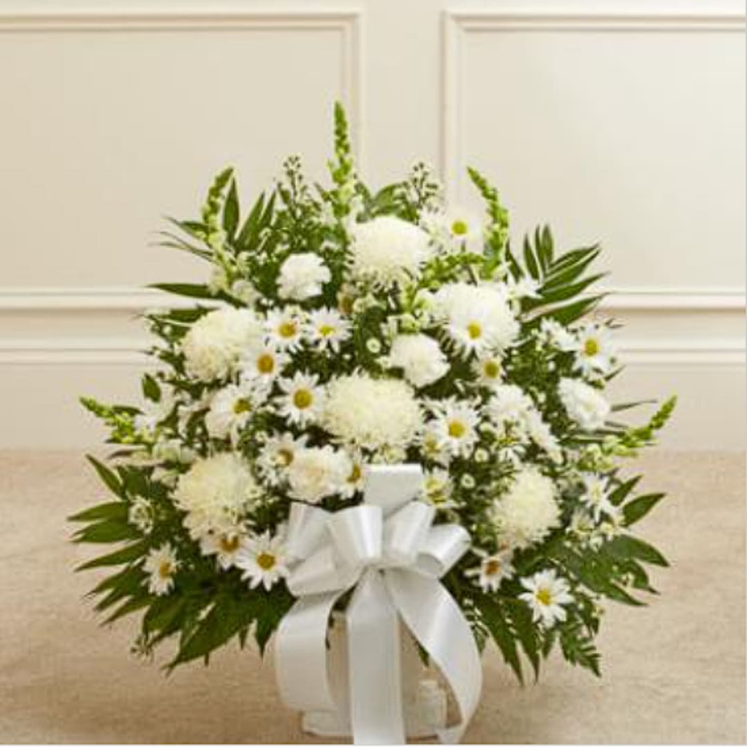 White floral arrangement in a vase with a large white ribbon
