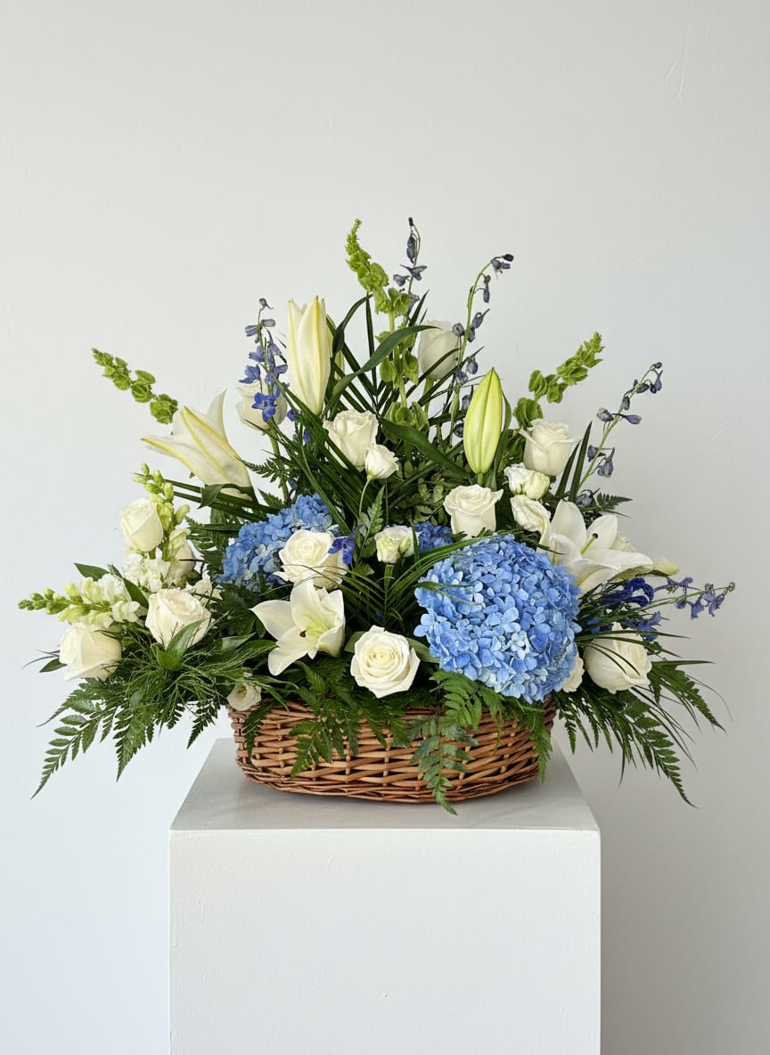 Sympathy Basket  - A sympathy arrangement in a basket is a warm and comforting expression of care, thoughtfully designed to honor a loved one’s memory. Arranged in a keepsake basket, this design features a harmonious blend of fresh seasonal flowers, creating a soft and inviting display.  Unlike standing sprays, basket arrangements are versatile and suitable for both funeral services and delivery to the home of the bereaved. Their low, natural style makes them easy to place on a table or entryway, offering a gentle reminder of support during a difficult time.