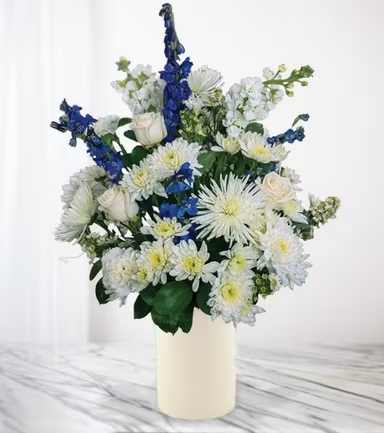 White and blue floral arrangement in a cream vase