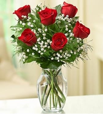 Red roses with baby's breath in a clear glass vase