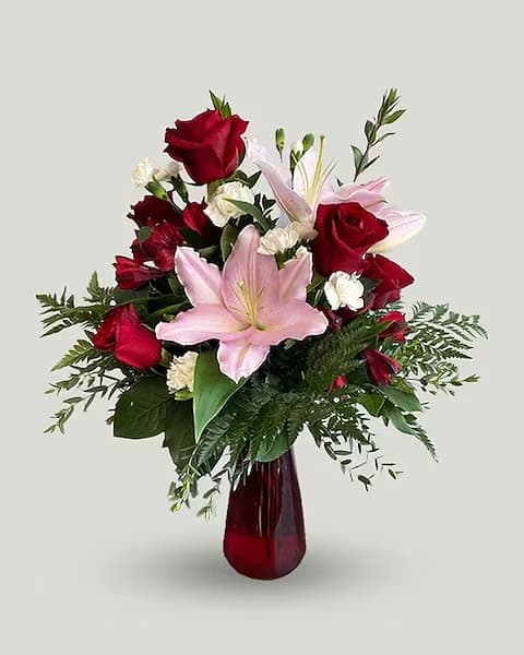 Red roses and pink lilies in a red glass vase