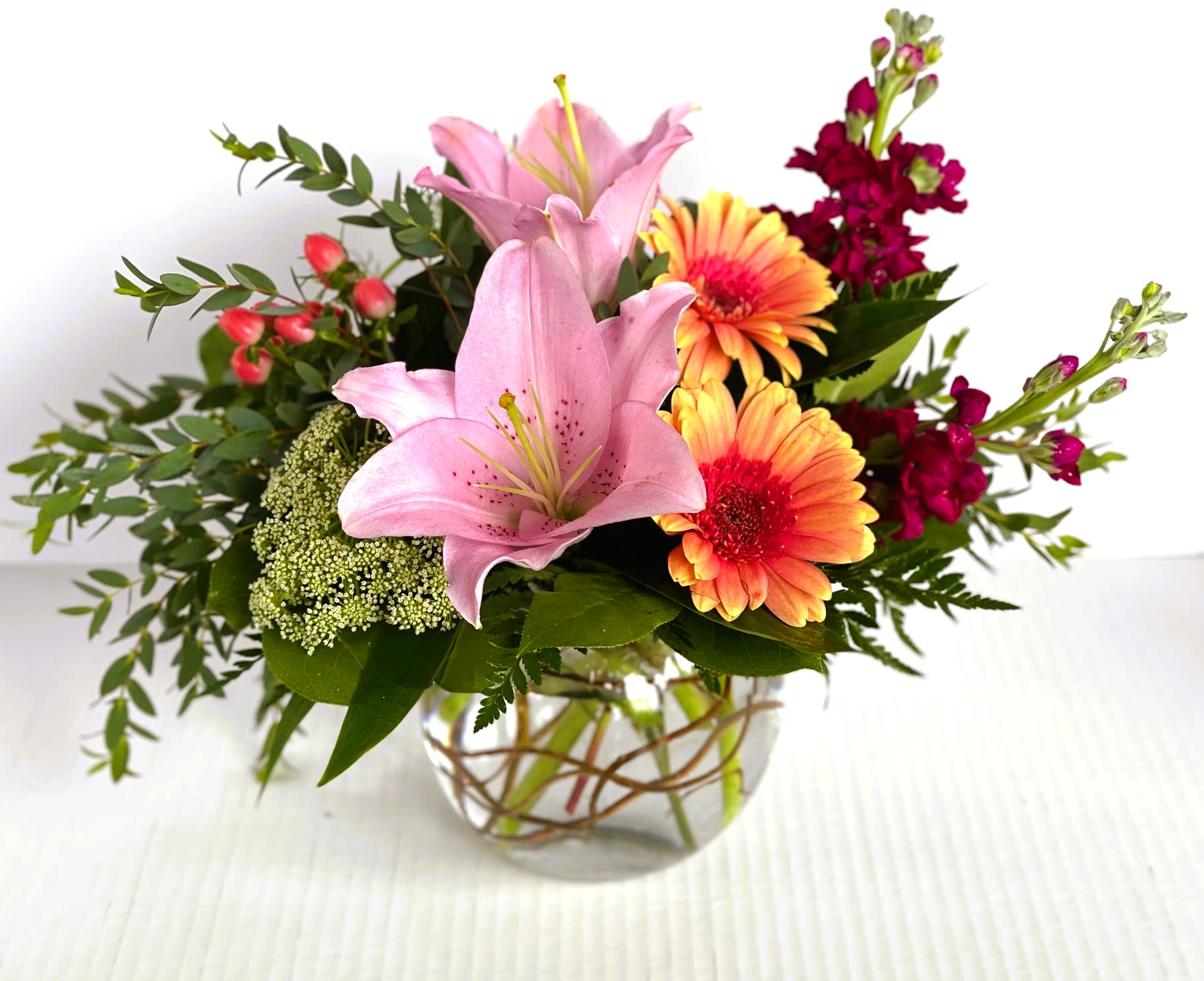 Garden Tea Party - Designed with gerbera daisies, stock, green mist or hydrangea, and lilies, this arrangement will definitely make an impression. This is styled in a bubble bowl with curly willow and makes this an enchanting arrangement for any occasion.
