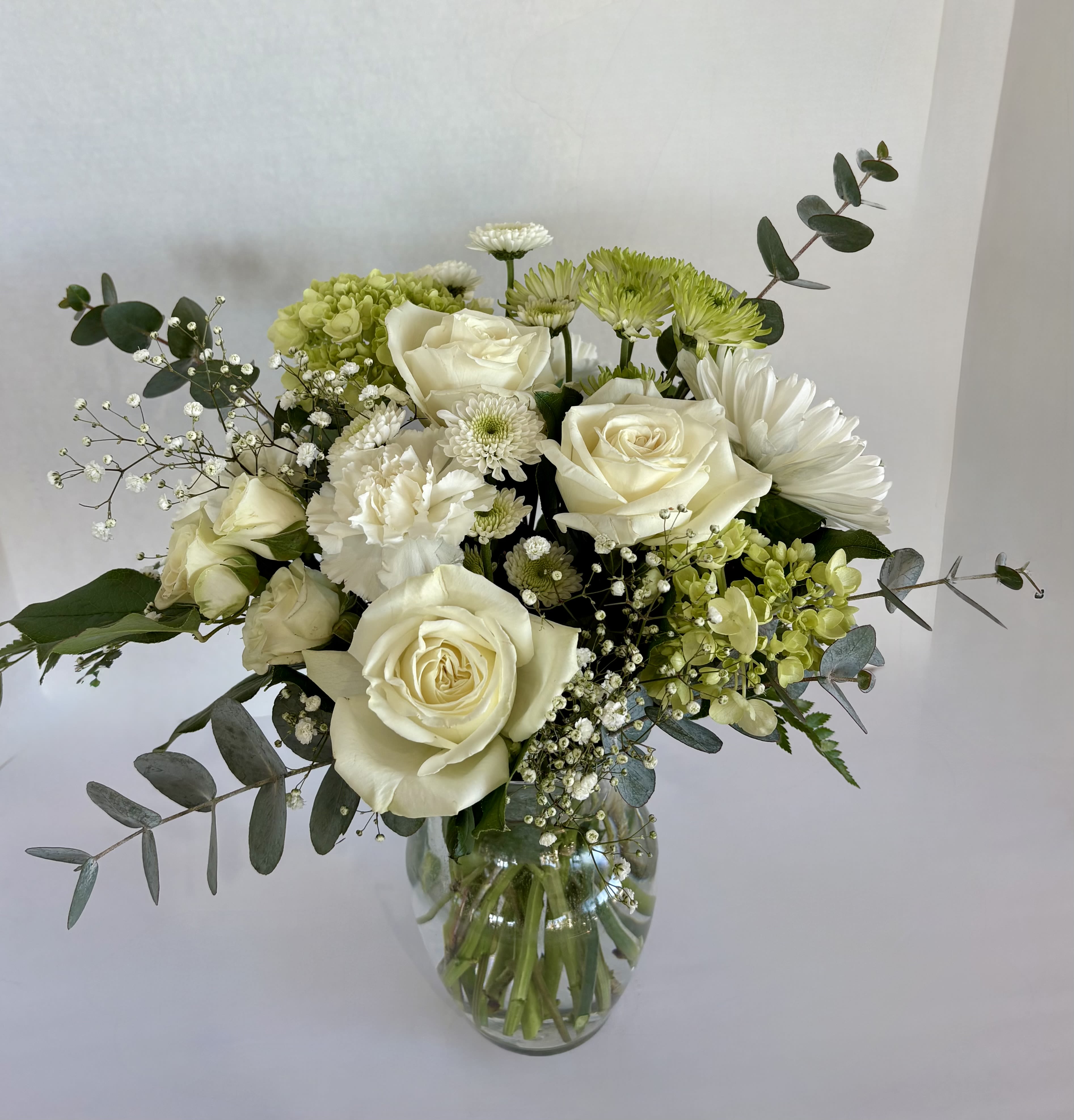 White roses and green chrysanthemums in a glass vase