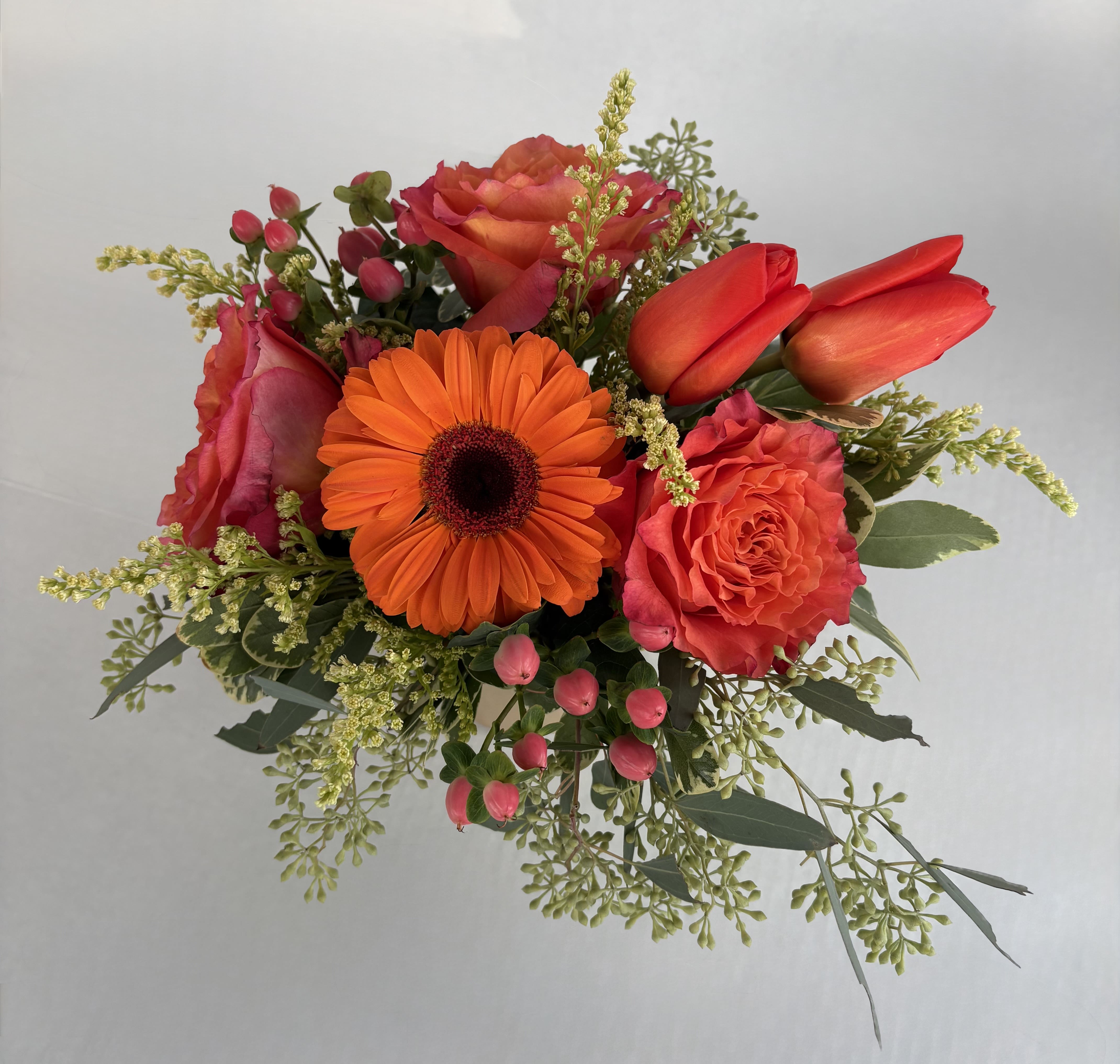 Bouquet of orange gerbera daisies, coral roses, and red tulips