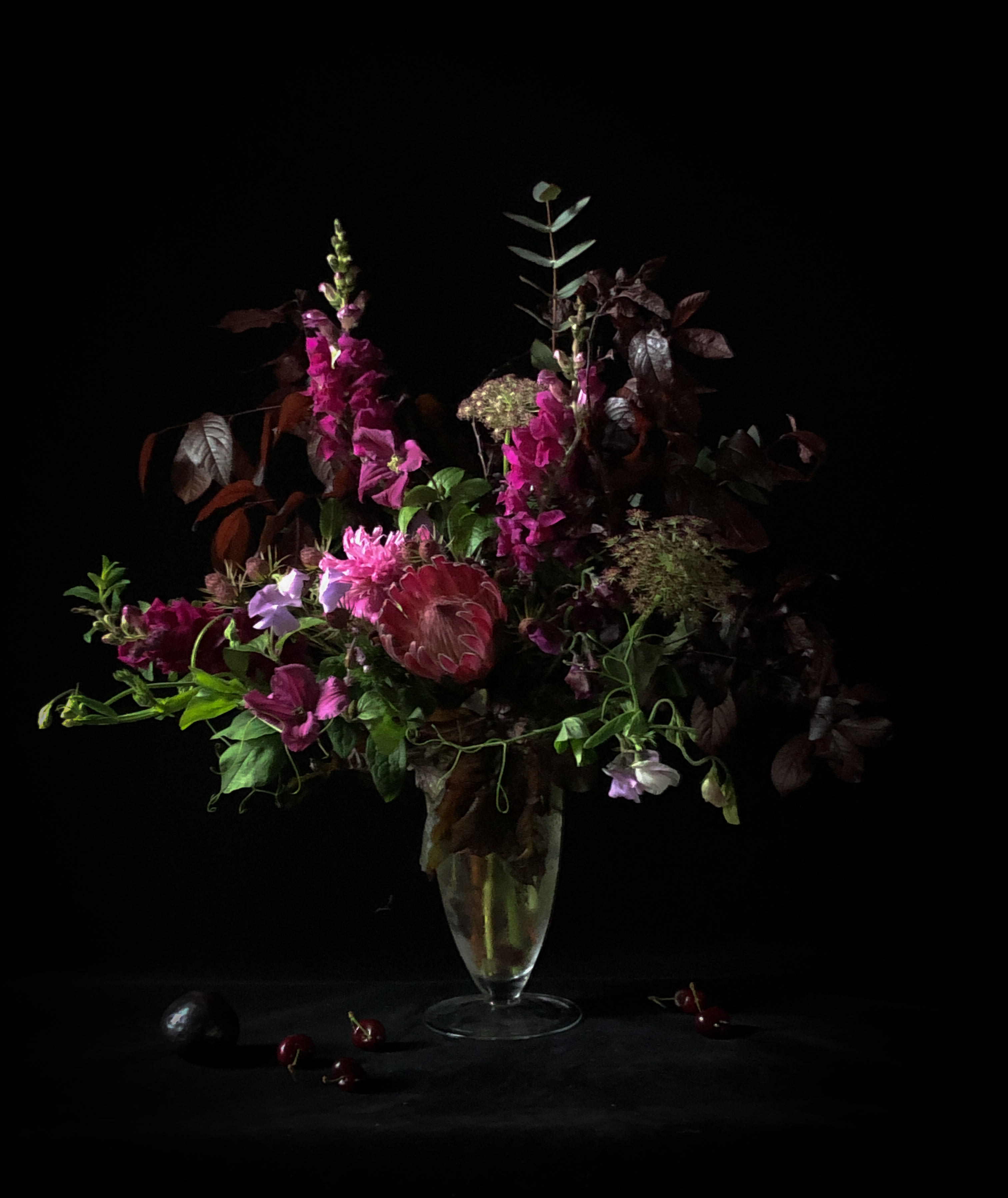 Tall magenta and purple floral arrangement in a clear vase