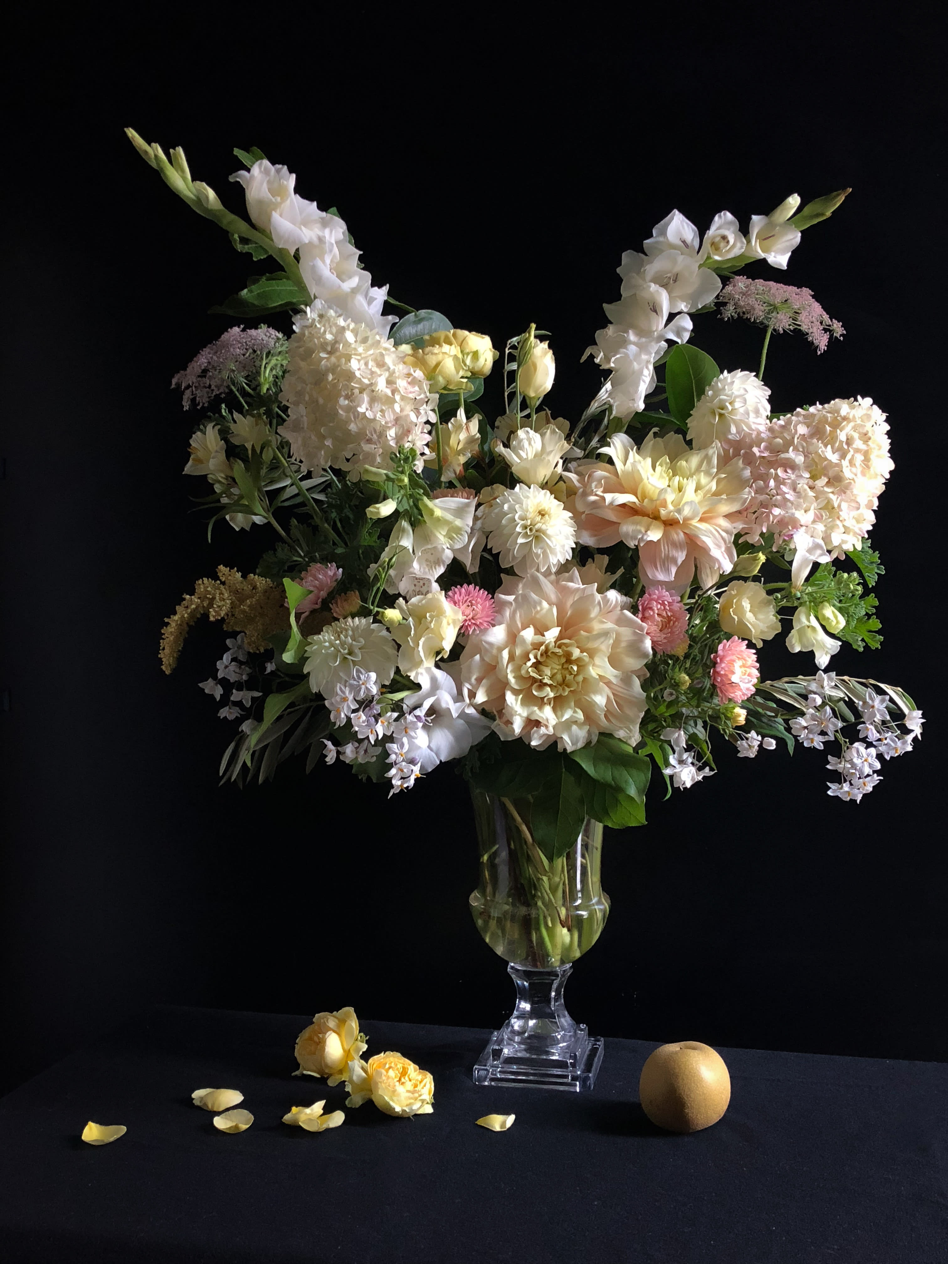 Tall pastel floral arrangement in a clear glass vase with white and blush blooms