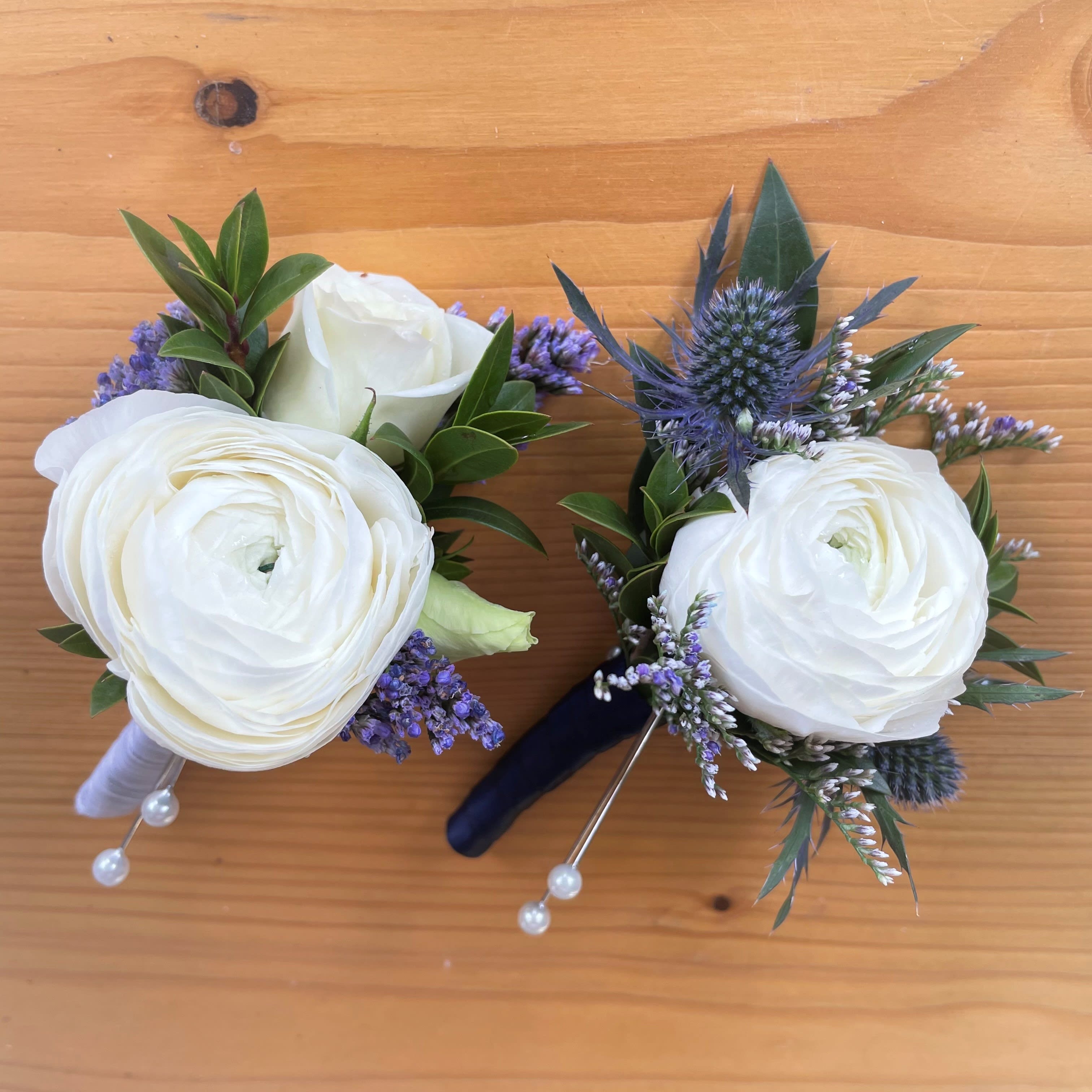 Ranunculus Boutonniere - Pick Up Only - Boutonniere featuring a ranunculus with accent flowers and foliage. We can customize these based upon the suit/dress colors. Please note in the special instructions if you have a color preference for the accent flowers and ribbon wrapped stem. If there are no notes we will make the bout in all white with a black satin wrapped stem.  Please note that corsages and boutonnieres are non-refundable after being made. 