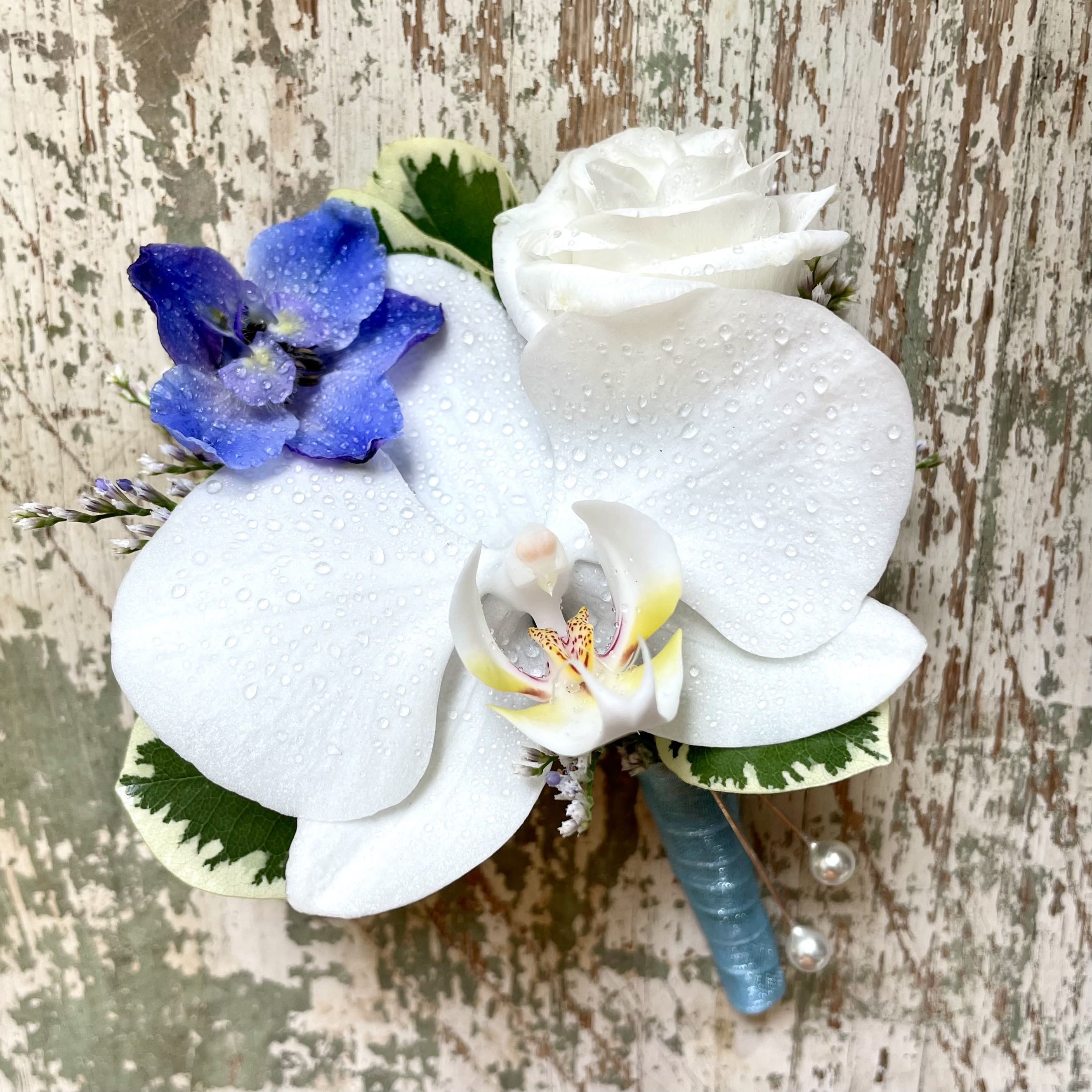 Orchid Boutonniere - Pick Up Only - White phalaenopsis orchid boutonniere with accent blooms. Please note any special flower colors or ribbon colors in the 'Special Instructions' box.   Please note that corsages and boutonnieres are non-refundable after being made. 