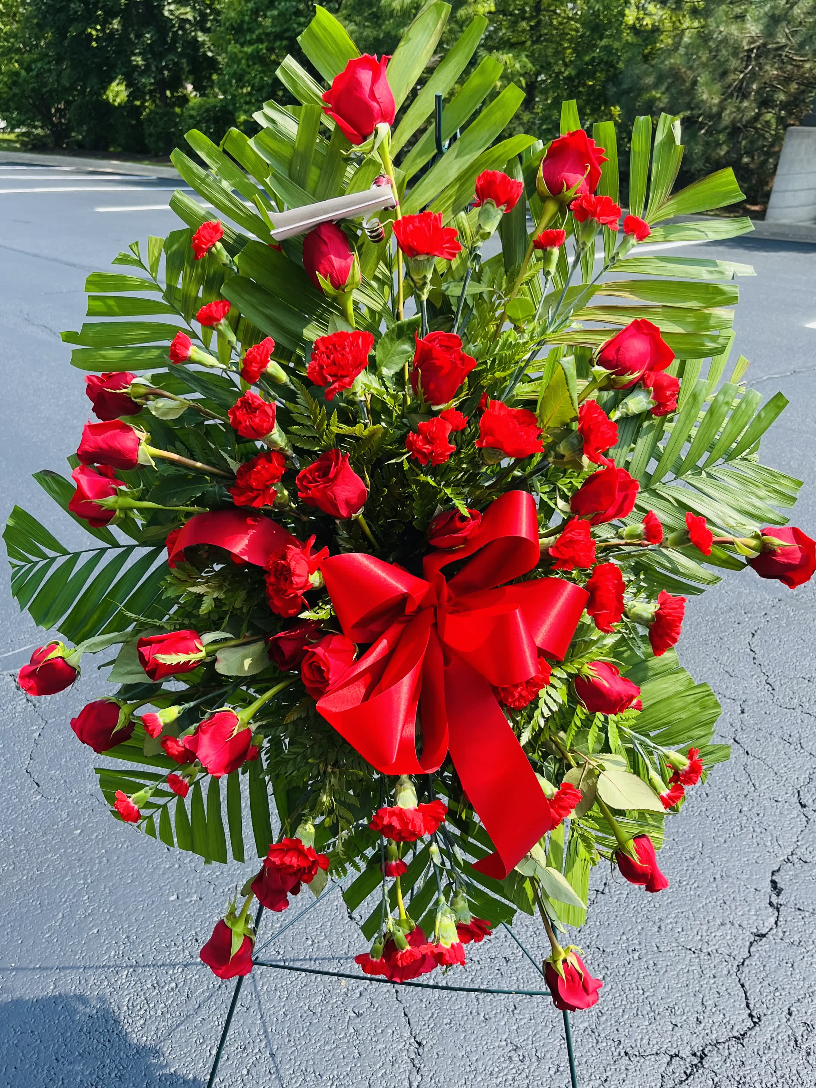 Large red rose and carnation standing spray with a red bow