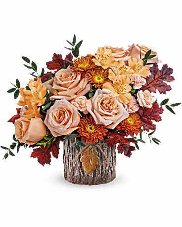 Autumn bouquet of peach roses and orange mums in a rustic wood vase