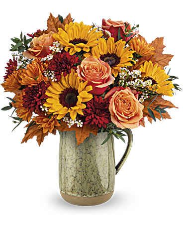Bouquet of sunflowers, roses, and autumn flowers in a ceramic pitcher