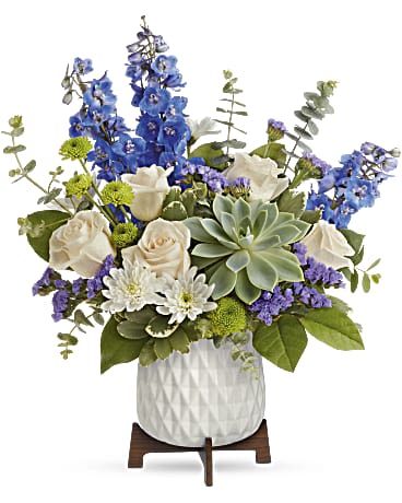 Blue and white floral arrangement in a white vase with a succulent