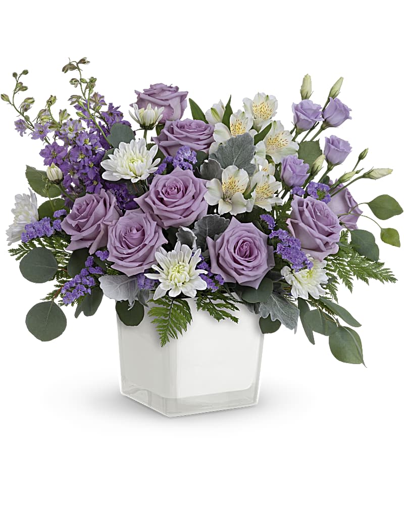 Lavender roses and white flowers in a clear square vase