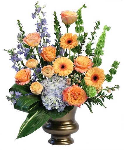Mixed bouquet of orange roses, gerbera daisies, and blue flowers in a gold vase