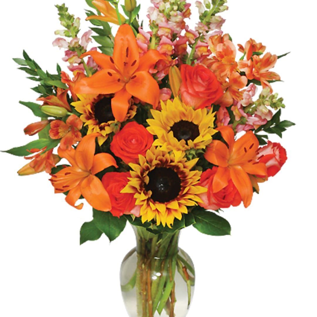 Orange lilies, roses, and sunflowers in a glass vase
