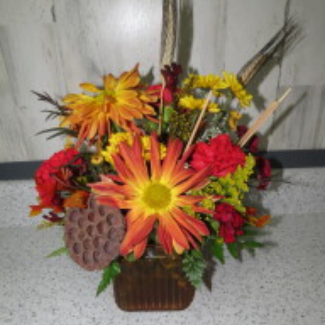 Orange and red mixed flower arrangement in a brown basket