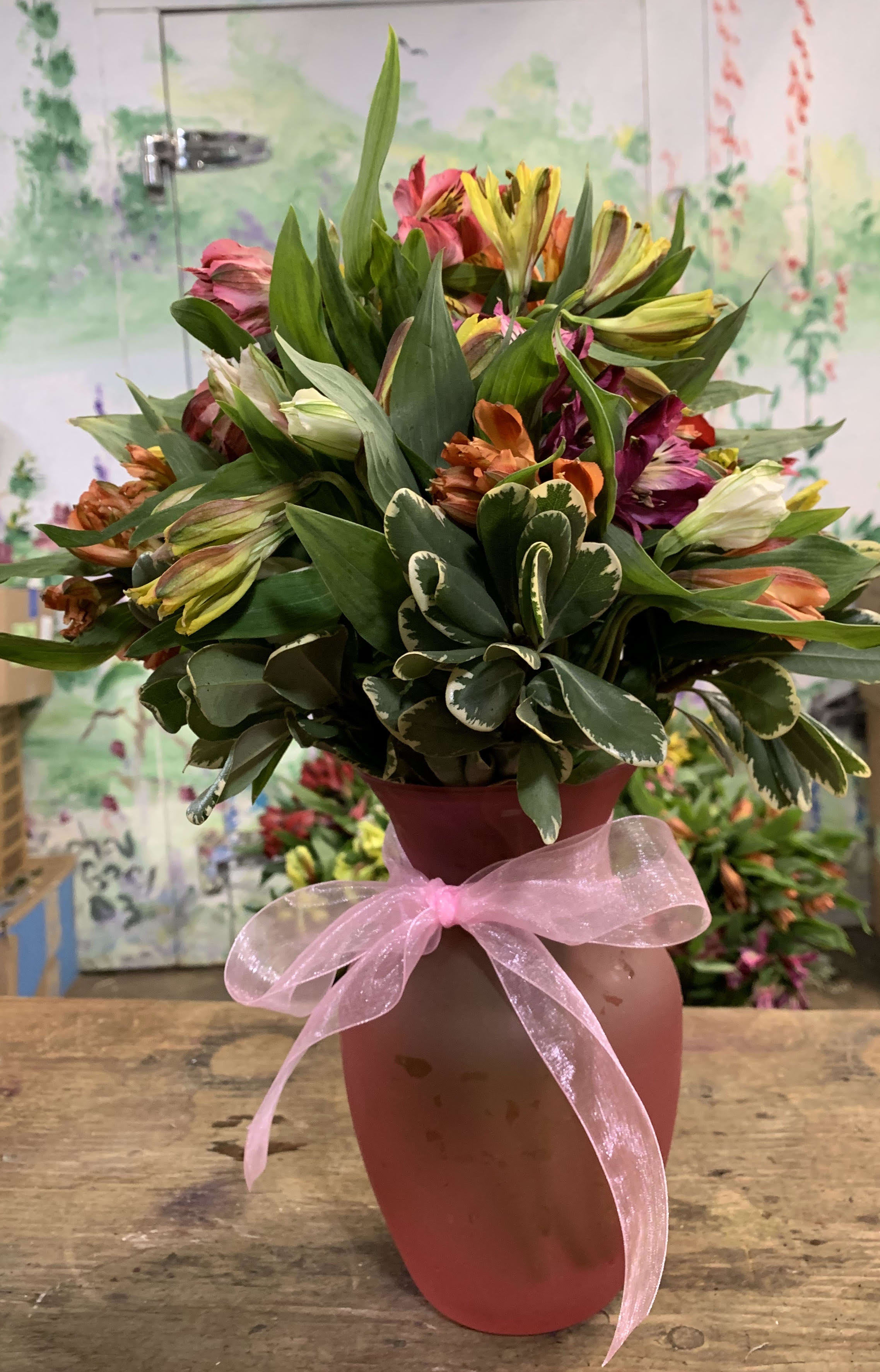Mixed bouquet in a pink vase with a pink ribbon