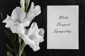 White flowers beside a sympathy card on a black background