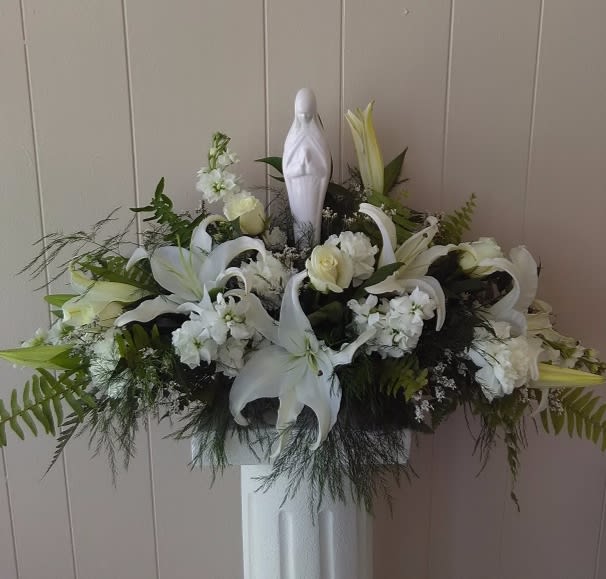 9010 Bouquet of Eternal Love with Madonna - Bouquet of Eternal Love.  This is an flawless arrangement that will bring a luminous beauty to any life's most precious moments.  An exquisite Madonna is surrounded by Oriental Lilies, White Stock and a vibrant blend of lush greens to create a wonderful arrangement ideally suited for a communion, memorial service, or even a wedding. ***Pictured as Deluxe***  7"h x 28"w