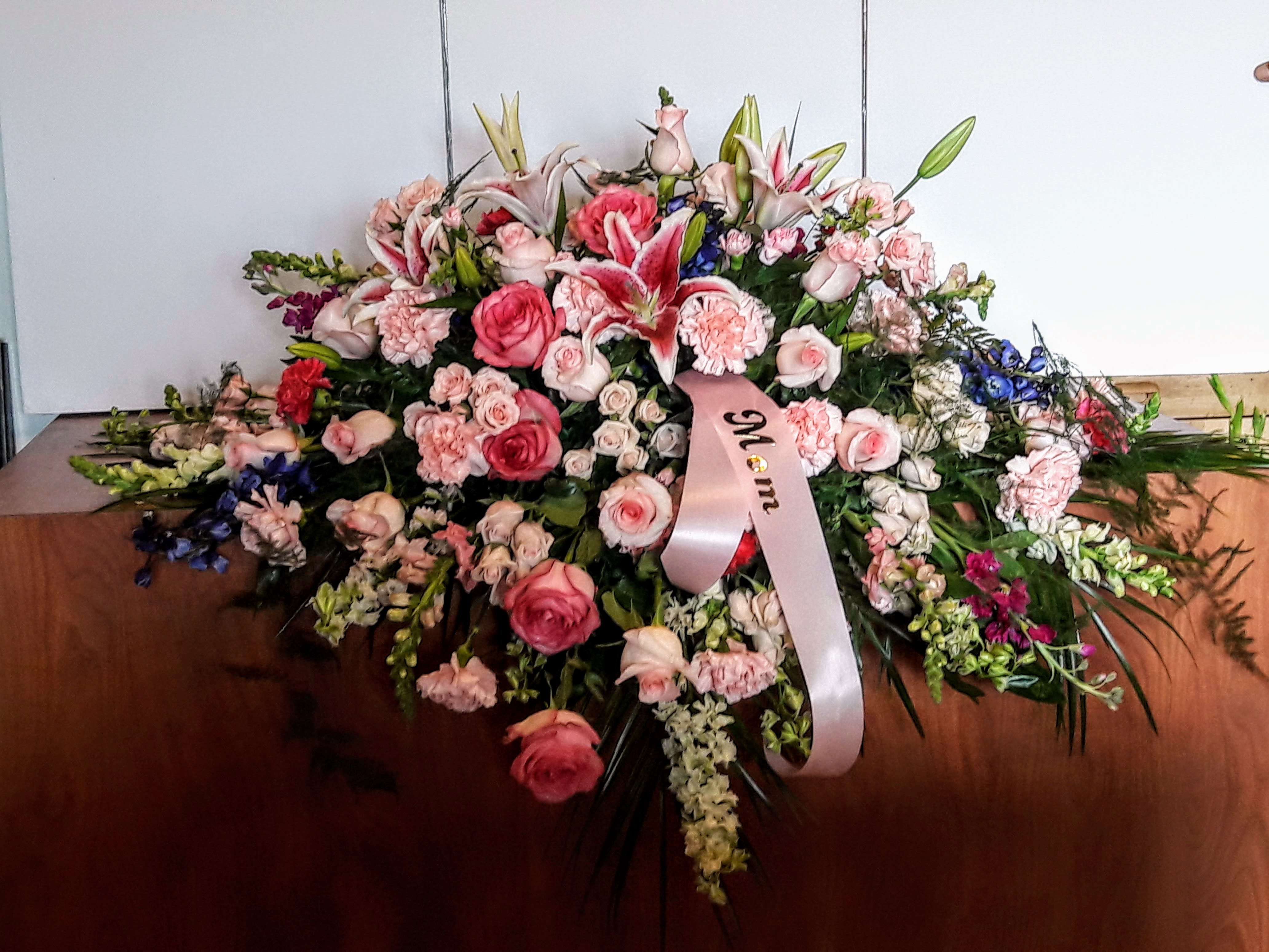 Large pink and white floral spray with a memorial ribbon