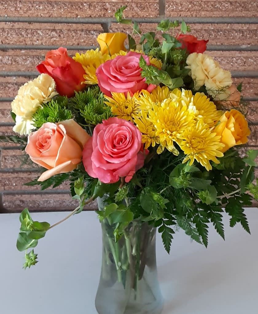 Mixed bouquet of roses and yellow chrysanthemums in a glass vase