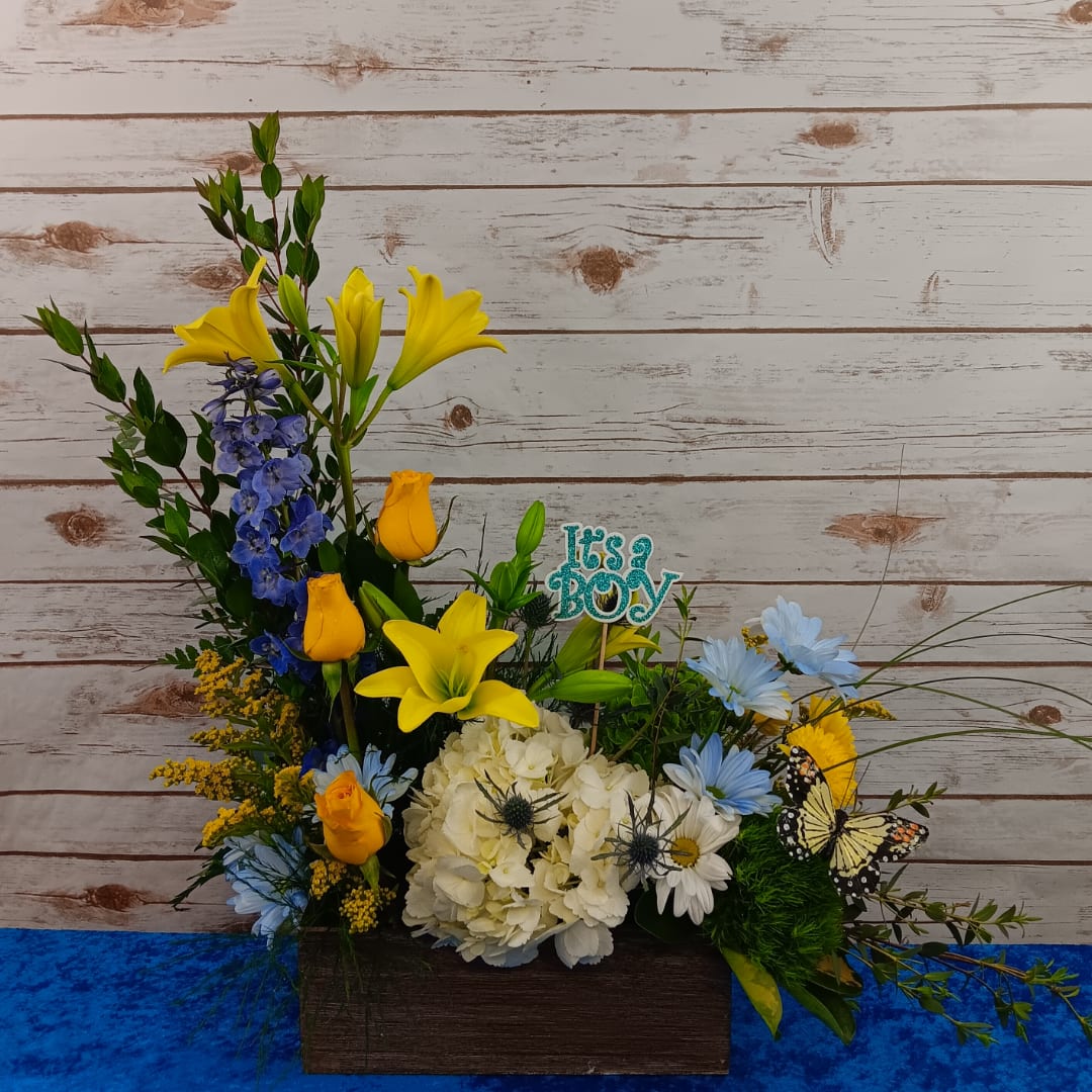 Mixed floral arrangement with yellow lilies, blue flowers, and white hydrangea in a wooden box