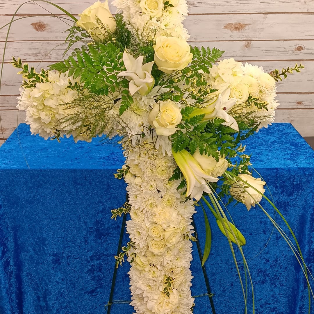 White floral cross arrangement with roses, lilies, and chrysanthemums