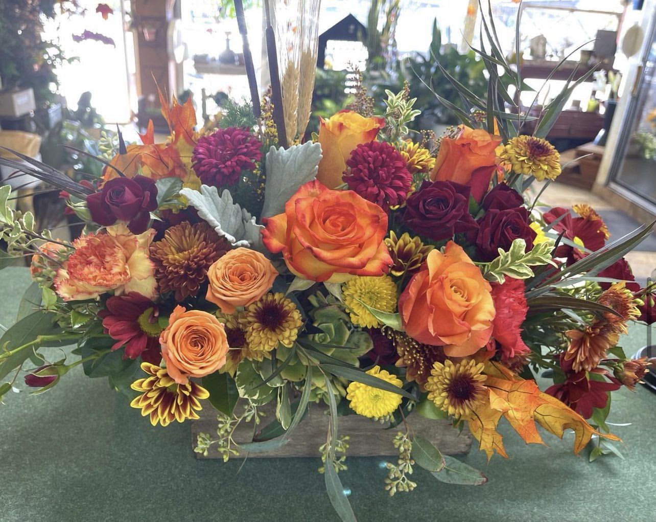 Fallen for you - A seasonal mixture of fall flowers in a wooden box . Includes roses, Pom poms, daisies and other fall flowers. 