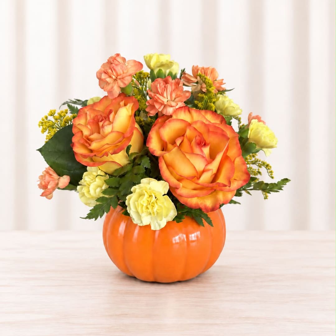 Orange and yellow flower arrangement in a pumpkin-shaped container