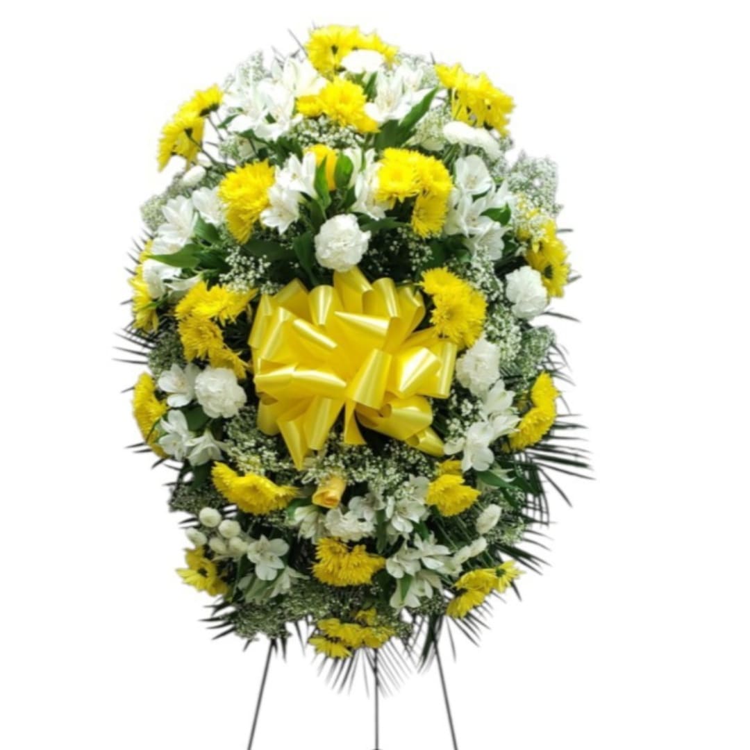 Yellow and white funeral wreath with a large yellow bow on a stand