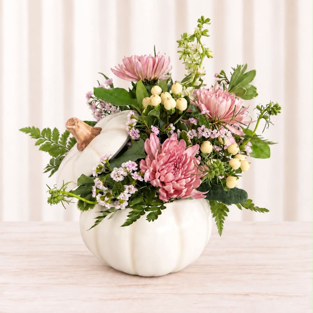 Pink flowers arranged in a white pumpkin-shaped vase