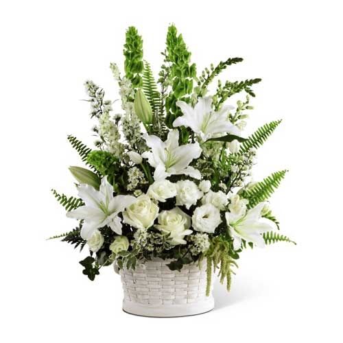In Our Thoughts Flower  Basket - A symbol of pure peace and caring kindness. White roses, tulips, freesia, Oriental lilies, double lisianthus, Monte Casino asters and snapdragons are beautifully offset by bright green Bells of ireland, ivy vines, and an assortment of lush greens to create an elegant display that conveys your deepest sympathies for thier loss. Arrives in a large round whitewash basket.