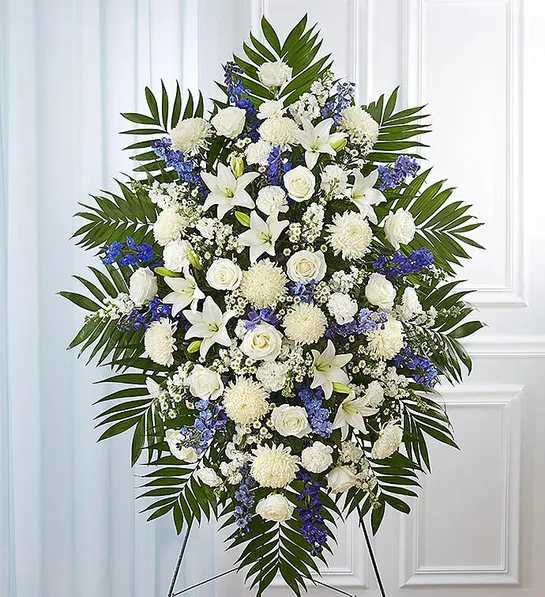 Blue &amp; White Funeral Standing Spray - When someone so dear passes, a standing tribute is a fitting way to pay respects. Our impressive standing spray arrangement, meticulously handcrafted by expert florists with pristine white and rich blue blooms, is a lush, full presentation that makes for a proud and respectful commemoration.