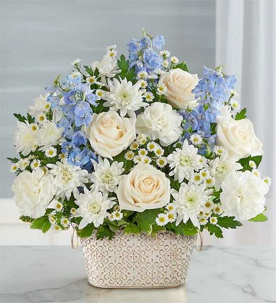 Loving Remembrance  Blue and White - Celebrate the life of a loved one with our beautiful floral tribute. A mix of blooms in soothing shades is a symbol of enduring love. Designed in our Remembrance Cachepot, featuring an embossed pattern and finished with a gold brushed ivory surface.