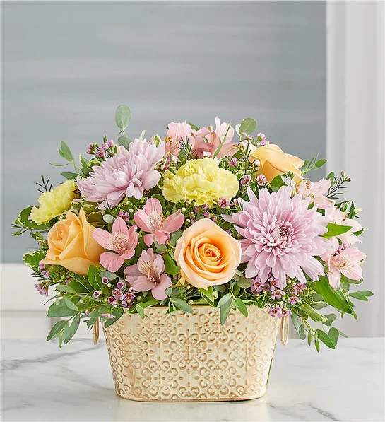 Loving Remembrance  Multicolor Pastel - Celebrate the life of a loved one with our beautiful floral tribute. A mix of blooms in soothing pastel shades is a symbol of enduring love. Designed in our Remembrance Cachepot, featuring an embossed pattern and finished with a gold brushed ivory surface.