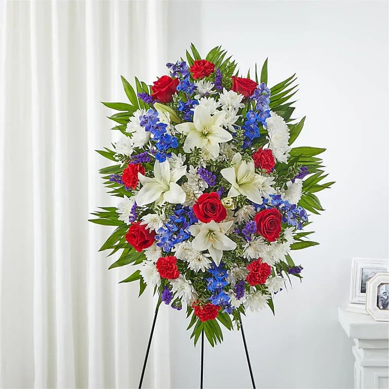 Standing floral spray with red roses, white lilies, and blue flowers