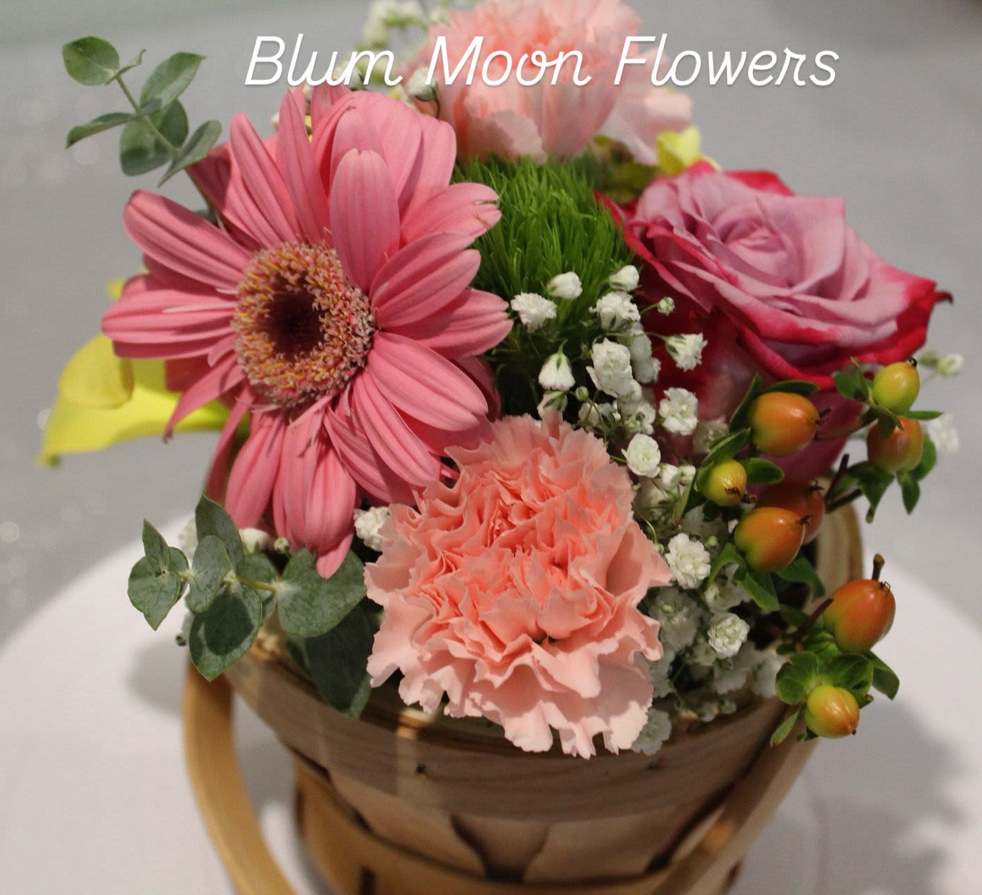 Pink flowers arranged in a basket with a rose and gerbera daisy
