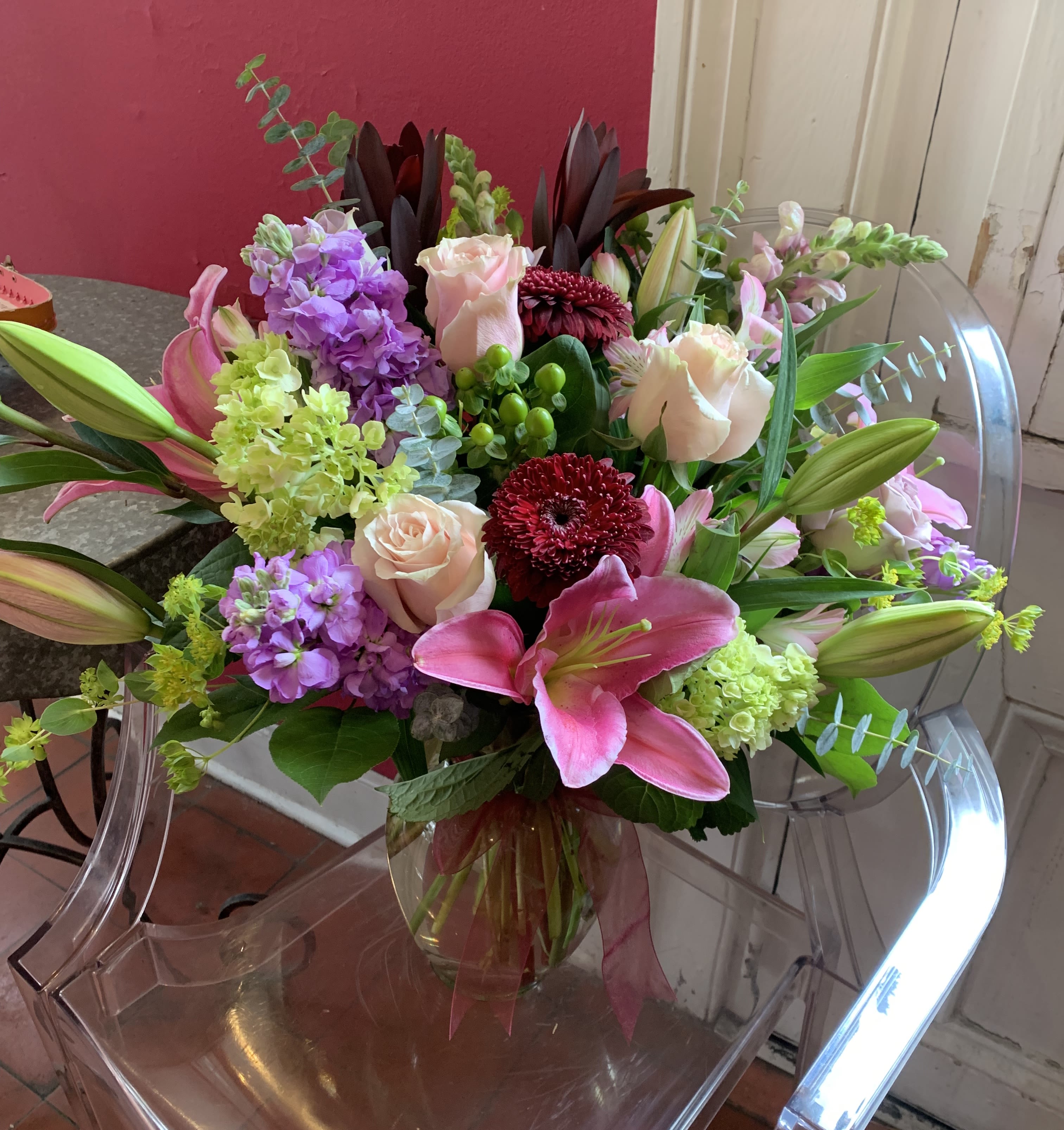 Bouquet of pink lilies, roses, and purple flowers in a glass vase