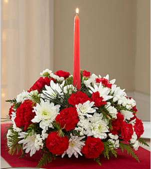 Merry Times Holiday Centerpiece - Picked fresh from the farm to bring an elegant glow to your holiday table, the Merry Times Holiday Centerpiece has a festive grace and beauty you are sure to love. Hand gathered at select floral farms and bringing together rich holiday reds, crisp whites and lush greens to form an eye-catching arrangement, this stunning centerpiece has been picked fresh for you to help you bring blooming beauty to your Christmas gathering or send your warmest season's greetings to friends and family near and far. Centerpiece includes: white chrysanthemums, red carnations, red mini carnations, white statice, lush holiday greens and a single red taper candle at the center. Approx. 7"H x 12"W.  Your purchase includes a complimentary personalized gift message.