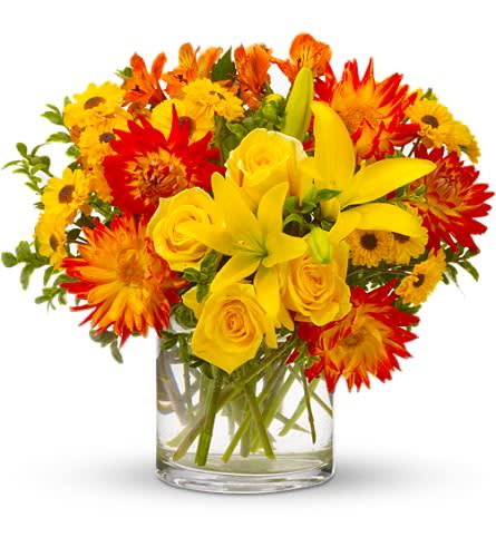 Yellow roses and lilies with red-orange daisies in a glass vase