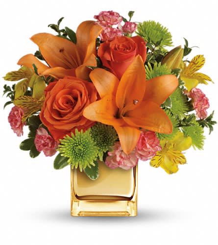 Teleflora's Tropical Punch Bouquet - Glow for it! Capture the magic of a tropical sunset with this gorgeously glowing bouquet. Lush lilies and roses in radiant shades of orange and yellow are presented in a golden Mirrored Cube for a touch of instant glam. Soft orange roses asiatic lilies and miniature carnations are arranged with yellow alstroemeria and green button spray chrysanthemums. Delicate oregonia and pittosporum add contrast. Delivered in a Mirrored Cube.Approximately 12" W x 11 1/2" H Orientation: One-Sided As Shown : TEV31-8ADeluxe : TEV31-8BPremium : TEV31-8C
