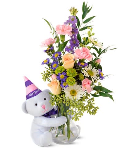Bouquet in a glass vase with a teddy bear wearing a party hat