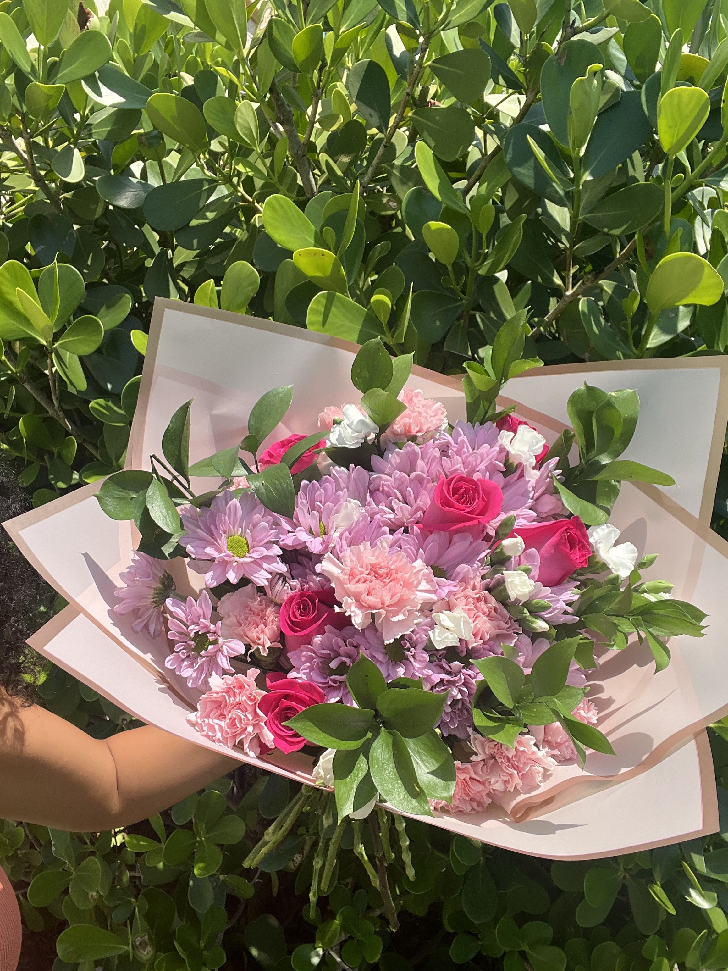 Pink and lavender bouquet with roses and daisies in pale wrapping