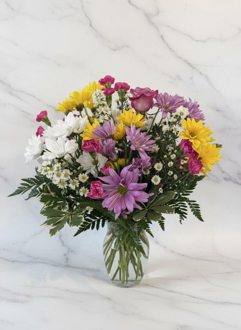 Mixed bouquet of daisies and roses in a clear glass vase