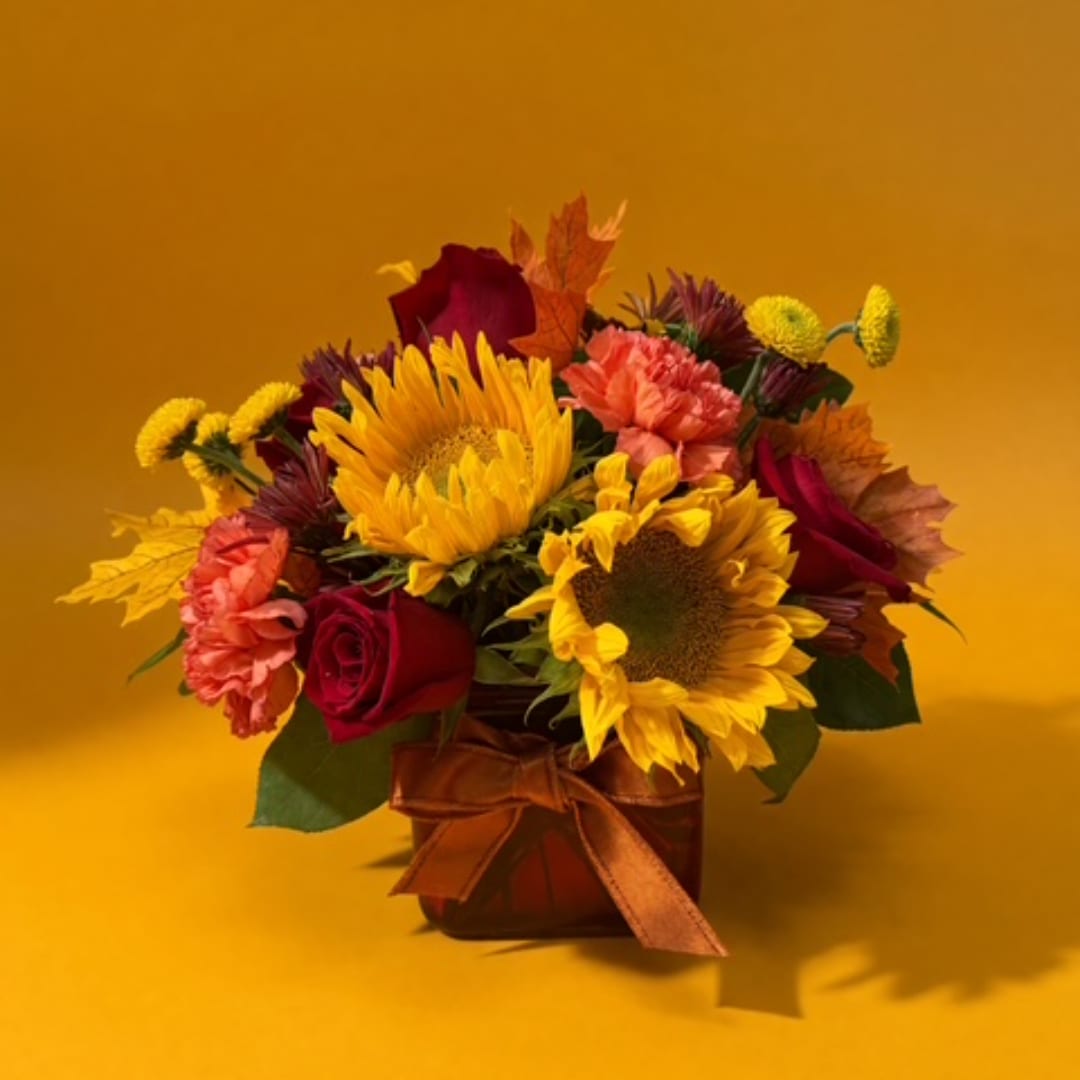 Bouquet of sunflowers, red roses, and carnations in a ribbon-tied vase